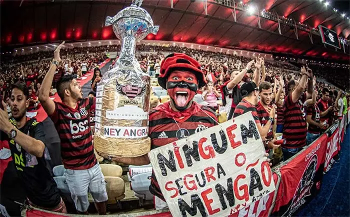 Torcida do Flamengo no Maracanã em noite de Libertadores com bandeiras rubro-negras